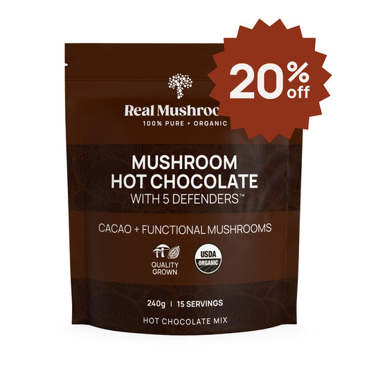 A brown package of Real Mushrooms' Mushroom Hot Chocolate Mix with a 20% off badge features sustainable heirloom cacao and organic mushroom extract, is USDA Certified Organic, weighs 240g, and offers 15 servings.