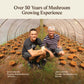 Two men kneel inside a greenhouse filled with rows of cultivated Reishi mushrooms. Above them, text reads: "Real Mushrooms: Over 50 Years of Growing Experience. Featuring RealRest—Reishi, Valerian, and Lemon Balm.