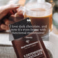 A hand holds a chocolate bar with "Mushroom Chocolate Bar - 5 Pack" packaging from Real Mushrooms, highlighting dark chocolate made from sustainable heirloom cacao. A coffee cup is situated in the background. A quote reads, "I love dark chocolate, and now it's even better with organic mushroom extract!