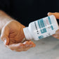 A person pours capsules from a Real Mushrooms Vitamin D from Organic Mushrooms bottle into their hand.