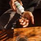 Someone pours Real Mushrooms Turkey Tail Mushroom Capsules, rich in beta-glucans, from the bottle into their hand over a wooden table with a glass of water to support immune health.