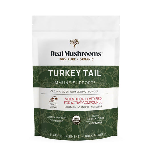 A white and green pouch labeled “Real Mushrooms Turkey Tail Extract - Bulk Powder” contains organic turkey tail mushroom powder for immune support, featuring vegan, non-GMO, gluten-free, and USDA organic certifications.
