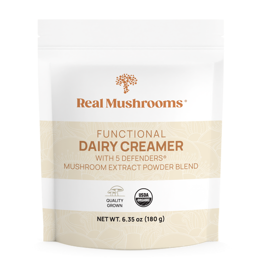 A white pouch labeled "Real Mushrooms Functional Dairy Creamer Powder" features an organic mushroom extract blend. It is gluten-free, USDA Organic, Quality Grown certified, with a net weight of 180g.