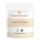 A white pouch labeled "Real Mushrooms Functional Dairy Creamer Powder" features an organic mushroom extract blend. It is gluten-free, USDA Organic, Quality Grown certified, with a net weight of 180g.